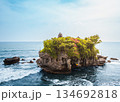 Tanah Lot temple Bali sea rock iconic landmark, ancient Hindu shrine on ocean cliff amid crashing waves lush greenery blue sky, exotic tropical Indonesian paradise coastal landscape travel destination 134692818