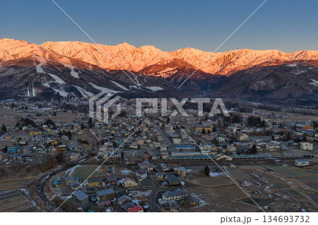 白馬三山の美しいモルゲンロートと白馬村の街並み　長野県白馬村（ドローンによる空撮） 134693732
