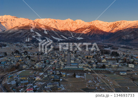 白馬三山の美しいモルゲンロートと白馬村の街並み 長野県白馬村(ドローンによる空撮) 白馬三山の美しいモルゲンロートと白馬村の街並み 長野県白馬村(ドローンによる空撮) 134693733