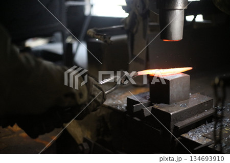 熱した材料を叩いて形を作る職人 134693910