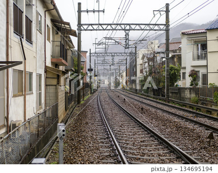 雨が降る住宅街を通る能勢電鉄妙見線の線路 134695194