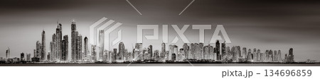 Urban city skyline with illuminated skyscrapers and waterfront railing in black and white at night, Dubai Marina bay UAE Urban city skyline with illuminated skyscrapers and waterfront railing in black and white at night, Dubai Marina bay UAE 134696859