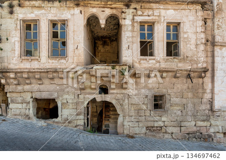 Old stone house facade with broken windows and arched entrance, Cappadocia, Turkey. Old stone house facade with broken windows and arched entrance, Cappadocia, Turkey. 134697462
