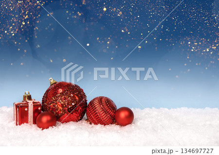 Christmas tree baubles on blue background with white snow and golden lights. Festive winter holiday background. Design with copy space for greeting card, text, advertising, banner, invitation Christmas tree baubles on blue background with white snow and golden lights. Festive winter holiday background. Design with copy space for greeting card, text, advertising, banner, invitation 134697727