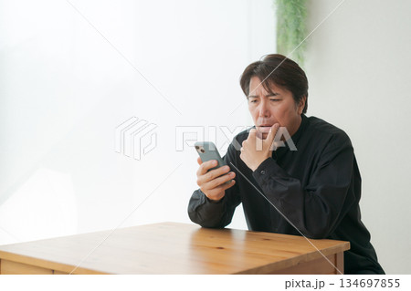 スマホを見て落ち込む中年男性 スマホを見て落ち込む中年男性 134697855