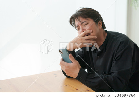 スマホを見て落ち込む中年男性 134697864
