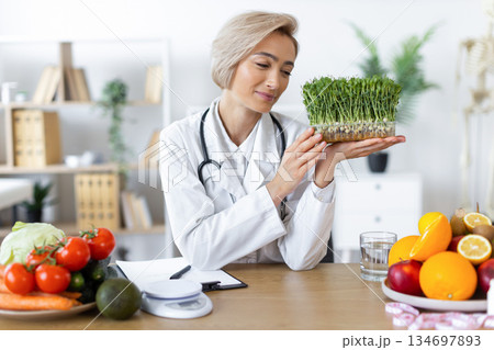 A nutritionist examines fresh sprouts, surrounded by healthy food choices, promoting a balanced diet. A nutritionist examines fresh sprouts, surrounded by healthy food choices, promoting a balanced diet. 134697893