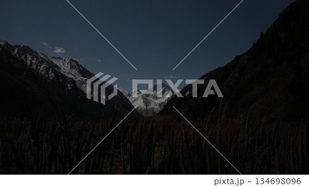 Majestic mountain landscape with snow-capped peaks and dark valley 134698096