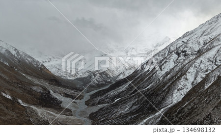 Snowy mountain valley landscape with dramatic clouds and river 134698132