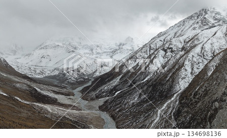 Snowy mountain valley landscape with river flowing through terrain 134698136