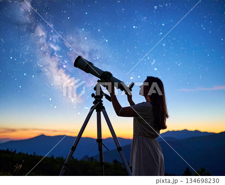 天の川が見える山の上の星空と望遠鏡を持つ人のシルエット 134698230