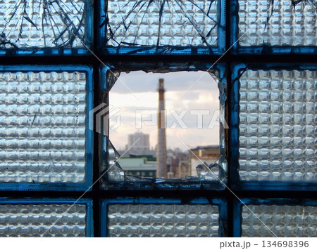 Industrial Plant Is Visible In A Damaged Glass Blocks With Bullets Holes 134698396