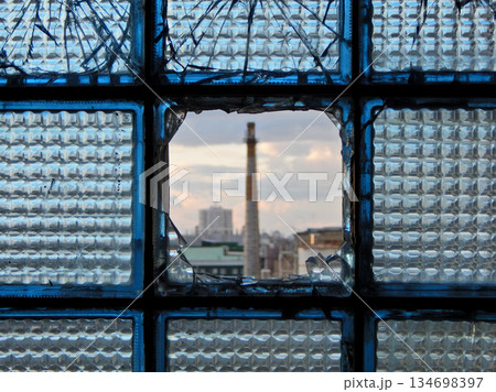 A factory seen in a broken glass block      134698397