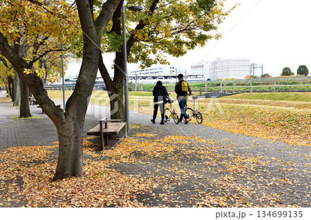 秋の横浜ポートサイド公園を自転車を引くカップル 134699135