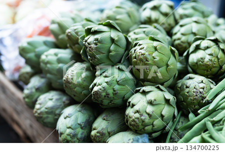 Pile of artichokes displayed on market counter Pile of artichokes displayed on market counter 134700225
