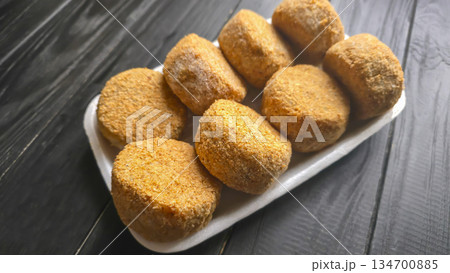 Freshly frozen breaded fish cakes. Round, semi-finished products, ready to cook. 134700885
