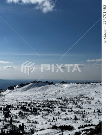 Wide snowy mountain view with blue sky and rocky peaks in winter. 134701462