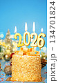 Happy New Year 2026, cute cake with golden ribbon with candle number 2026 for new year celebrate party was lit. decorated with Christmas ornament at blue background, vertical 134701824
