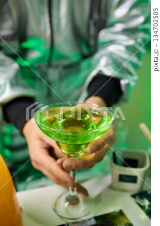 Vibrant lime cocktail presentation, Bartender displays colorful drink elegantly, Focus on bartender presenting vibrant green drink in stylish setting with soft lighting 134702505