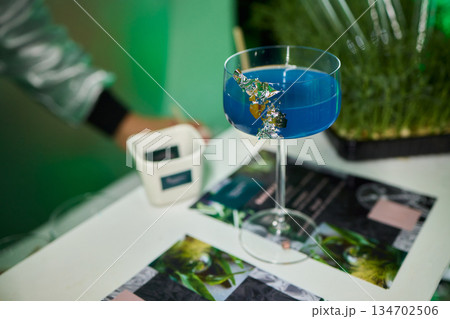 Vibrant lime cocktail presentation, Bartender displays colorful drink elegantly, Focus on bartender presenting vibrant green drink in stylish setting with soft lighting 134702506