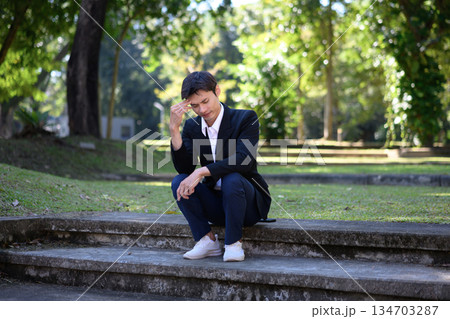 Office man stressed and sitting on outdoor steps in a green park Office man stressed and sitting on outdoor steps in a green park 134703287