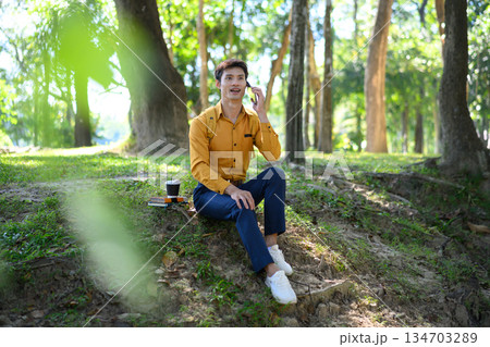 Office man sitting in a green park talking on the phone 134703289