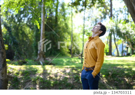 An office man stands in a green park breathing fresh air with a calm and relaxed mood An office man stands in a green park breathing fresh air with a calm and relaxed mood 134703311