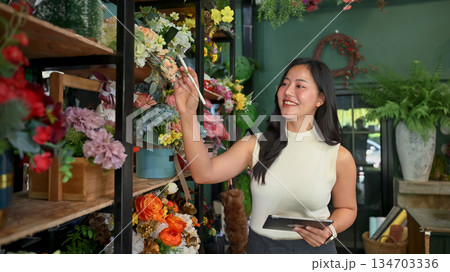 Florist business owner managing flower stock in her shop with a digital tablet Florist business owner managing flower stock in her shop with a digital tablet 134703336