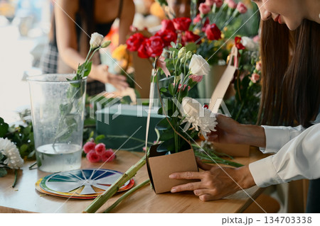 Group of people arranging colorful flowers together in a creative floral workshop Group of people arranging colorful flowers together in a creative floral workshop 134703338