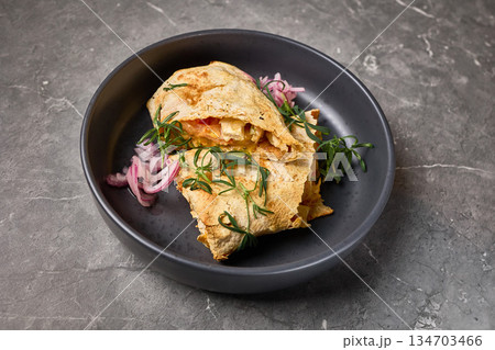 Delicious cheesy quesadilla with fresh herbs and onions served on dark plate, stone background, closeup view, Mexican food concept 134703466