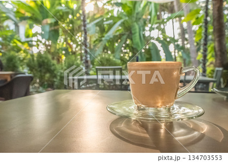 Coffee cup latte art on wooden table background with sunlight in a garden 134703553