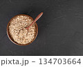 Oatmeal in a wooden bowl with a spoon on a black background 134703664