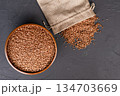 Bag and wooden cup with buckwheat on a black background 134703669