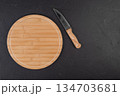 Round wooden cutting board with a knife on a black background 134703681