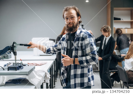 Job of clothing production. People are working by the sewing machines indoors Job of clothing production. People are working by the sewing machines indoors 134704250