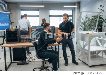 Conception of cooperation and communication. People are in the office by the 3d printer Conception of cooperation and communication. People are in the office by the 3d printer 134704380