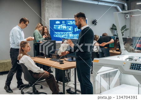 Conception of cooperation and communication. People are in the office by the 3d printer 134704391