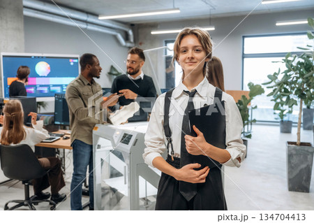 Woman is standing in front of colleagues. People are in the office by the 3d printer Woman is standing in front of colleagues. People are in the office by the 3d printer 134704413