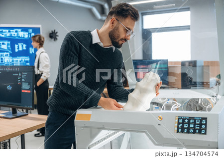 White printed object in hands. People are in the office by the 3d printer White printed object in hands. People are in the office by the 3d printer 134704574