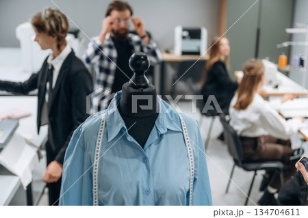 Mannequin in blue clothes. People are working by the sewing machines indoors 134704611