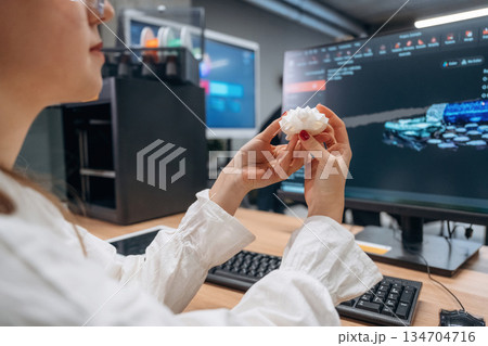 By computer, sitting. Woman is holding 3d printed toy turtle 134704716