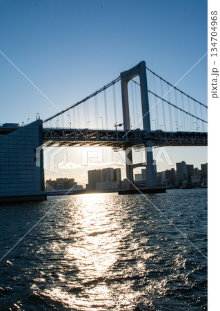 真っ青な快晴空の下眩しい太陽の光を浴びる東京湾にかかる大きなレインボーブリッジと東京都のビル群 134704968