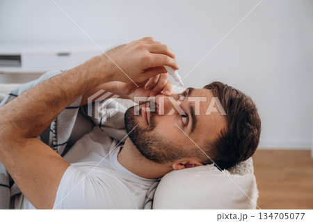 Eye drops, conception of vision. Sick man is feeling bad at home Eye drops, conception of vision. Sick man is feeling bad at home 134705077