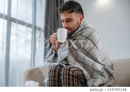 Cup in hand, drinking. Sick man is feeling bad at home 134705146