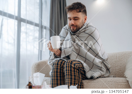 Cup in hand, drinking. Sick man is feeling bad at home 134705147
