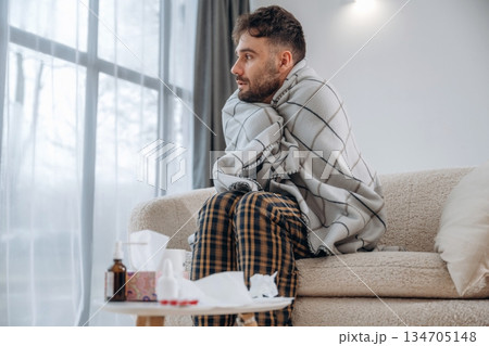 Looking to the side, medicine on the table. Sick man is feeling bad at home Looking to the side, medicine on the table. Sick man is feeling bad at home 134705148