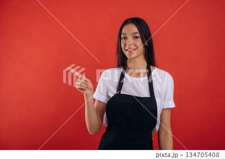 Pointing finger to a side. Young beautiful barista is against background 134705408