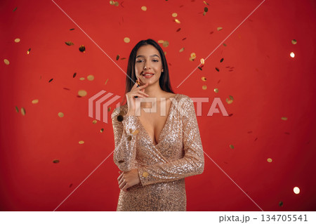 Looking forward, standing. Young elegant woman is against background Looking forward, standing. Young elegant woman is against background 134705541