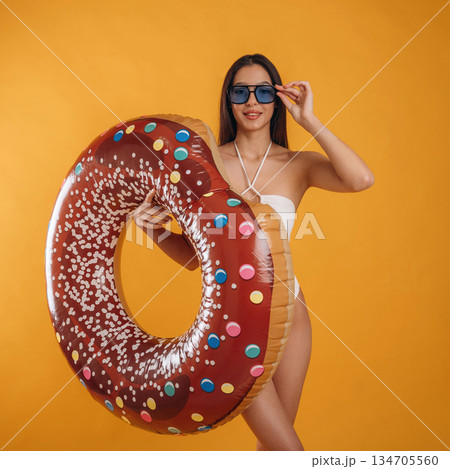 Swimming ring, looks like donut. Young beautiful tourist woman is against background Swimming ring, looks like donut. Young beautiful tourist woman is against background 134705560