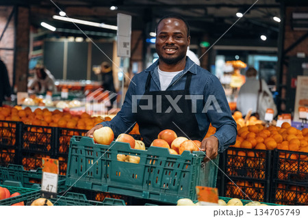 Tasty apples. Grocery store worker in apron is near products Tasty apples. Grocery store worker in apron is near products 134705749